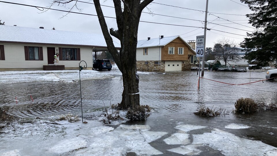 Au moins 10 cm d'eau recouvre la chaussée sur une rue résidentielle, en hiver.