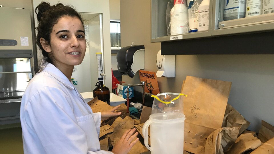 Une jeune femme pèse des éléments sur une balance dans un laboratoire.