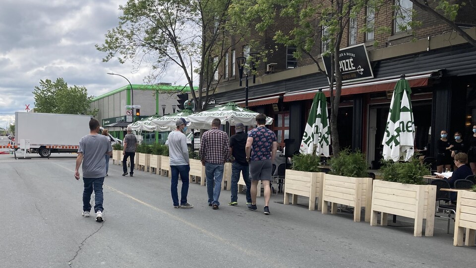 Des piétons marchent devant la terrasse du Pizzé.
