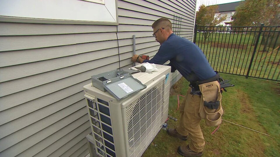 Une équipe de l'entreprise Greenfoot Energye est occupée à installer une mini-thermopompe. 