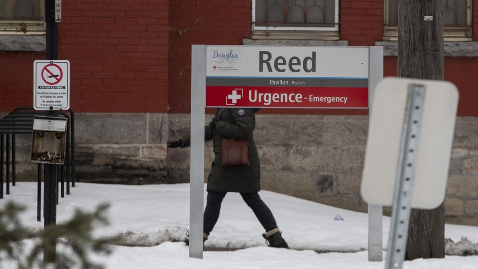 Une femme marche derrière un panneau annonçant l'urgence.