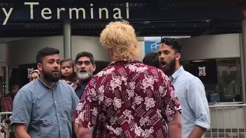 Photo d'un homme de dos qui fait face à trois hommes barbus.