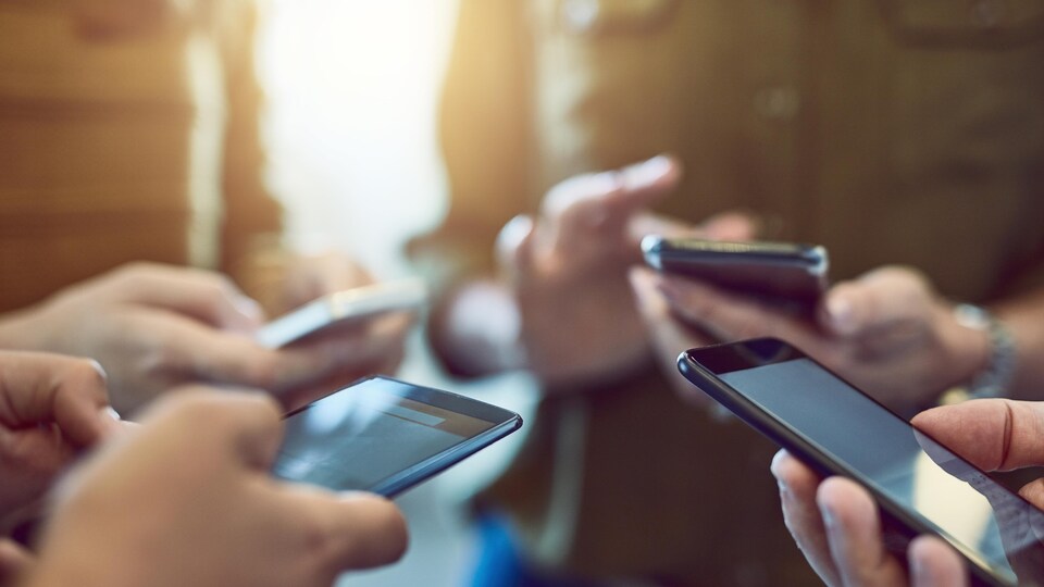 Quatre personnes tiennent des téléphones intelligents.