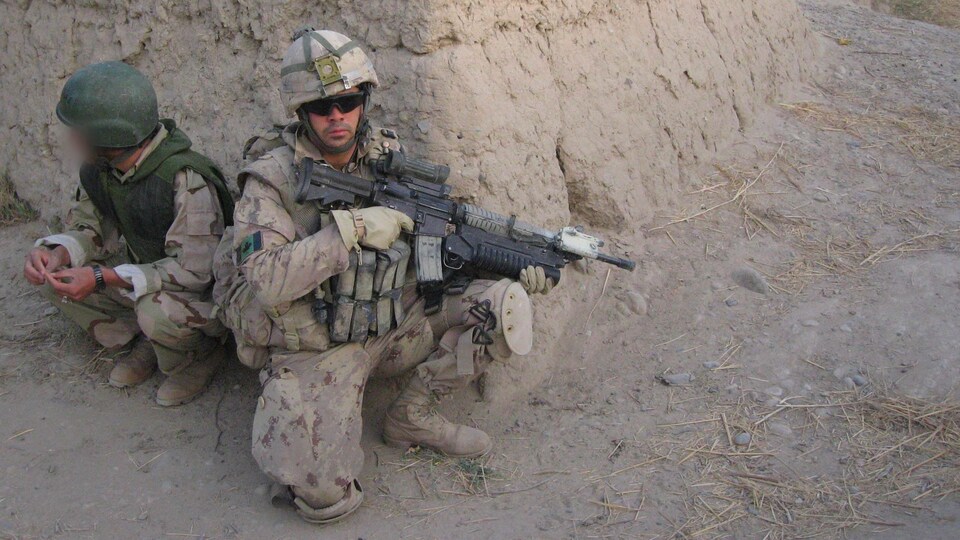 Un soldat, qui tient une arme dans ses mains, est accompagné d'un interprète.