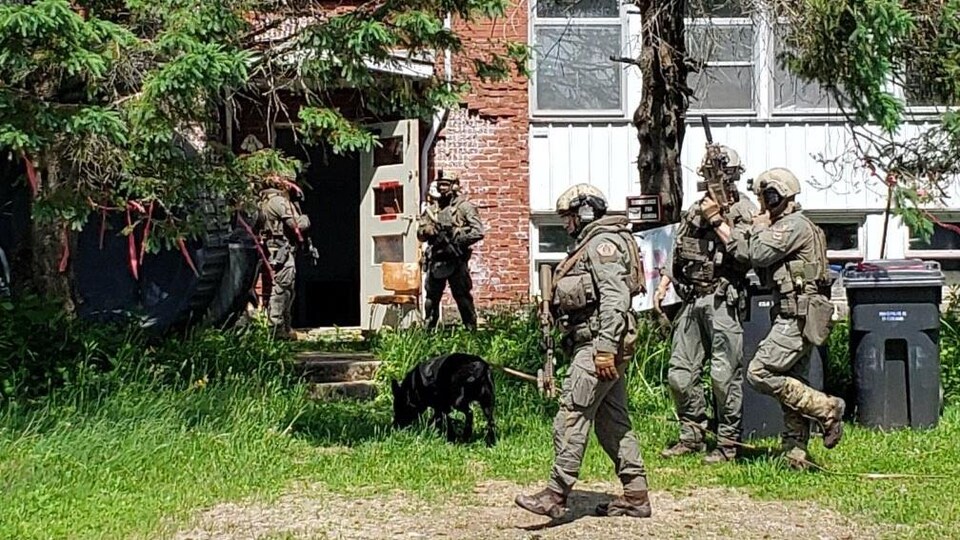 Des agents de la GRC lourdement équipés entrent dans un bâtiment.