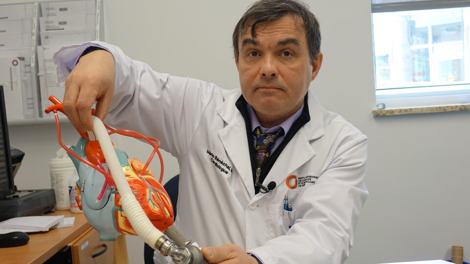 Le cardiologue Mario Sénéchal tient un cœur artificiel dans sa main.