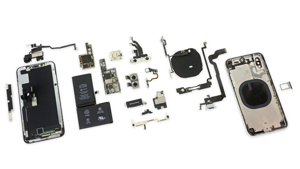 Un iPhone X ouvert en deux avec ses pièces éparpillées sur une table.