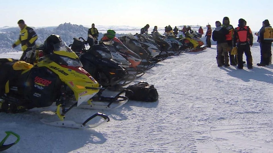 Several snowmobiles are parked in a row on the frozen bay of Frobisher.