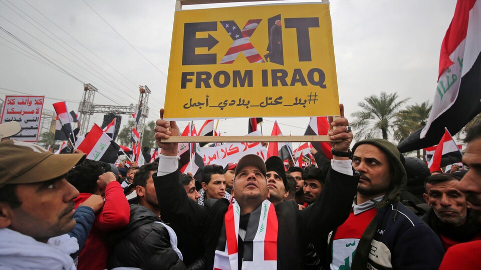 « Sortez d'Irak », peut-on lire sur une pancarte brandie par un manifestant. Des images du drapeau américain et du président Donald Trump sont visibles sur la pancarte.