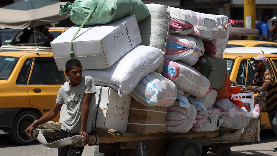 Un Irakien transporte des marchandises entassées sur une charrette.