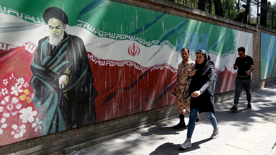 Des gens marchent près d'une murale présentant le fondateur de la République islamique d'Iran, l'ayatollah Rouhollah Khomeini.