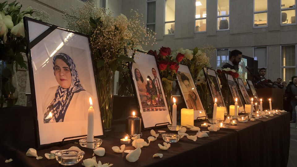 Des portraits des victimes sont posés sur une table avec des bougies.