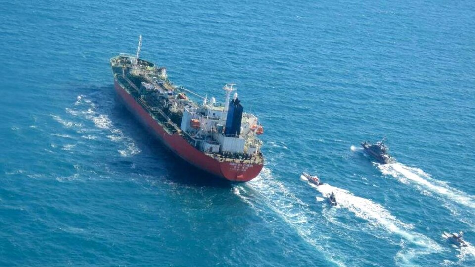 De petites embarcations voguent près d'un pétrolier.