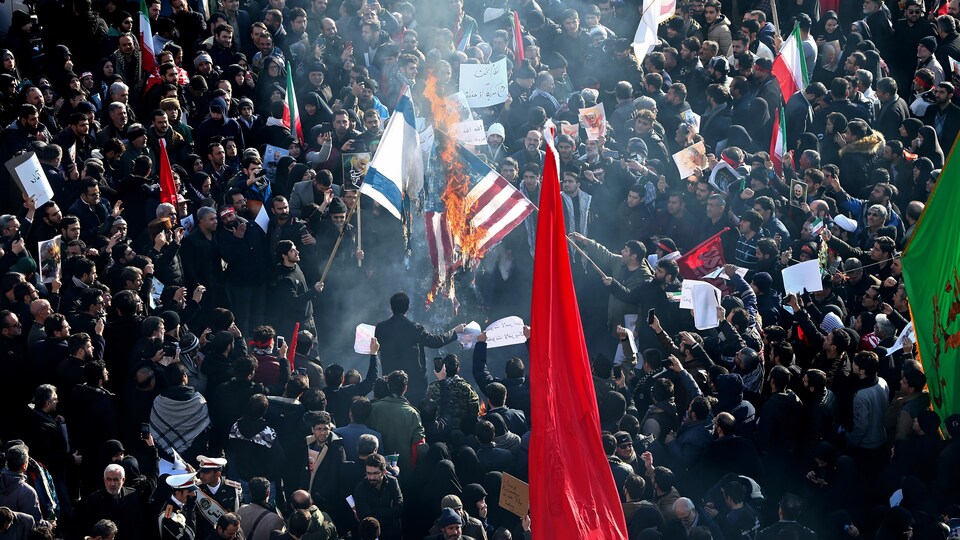 Une foule d'Iraniens brandit des drapeaux de l'Iran et brûle le drapeau américain.