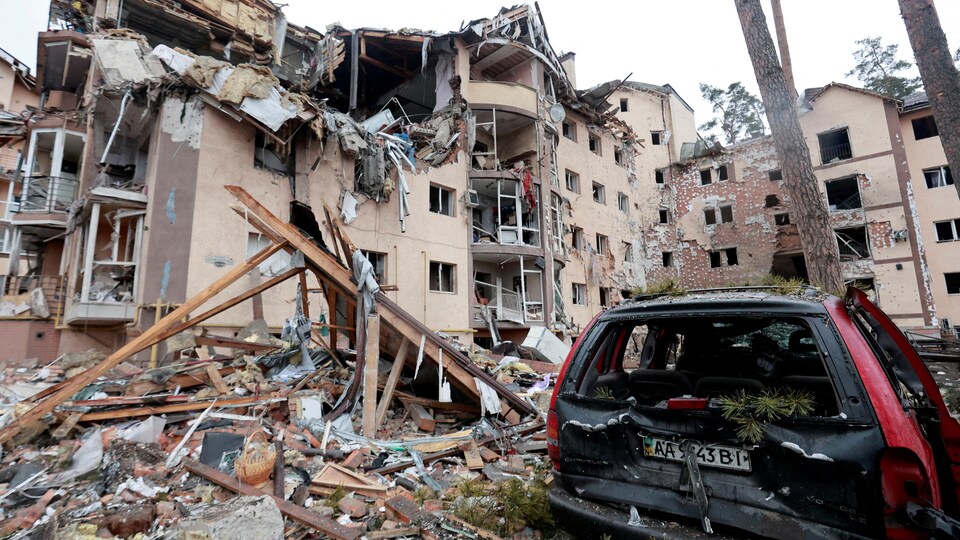 Un véhicule et des grands bâtiments complètement détruits par des bombes.