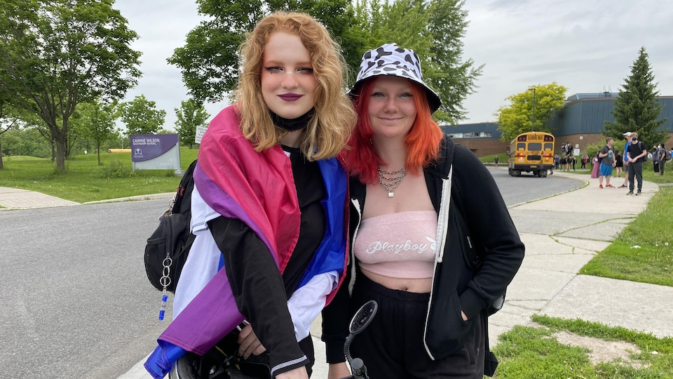 Deux jeunes femmes posent devant une école