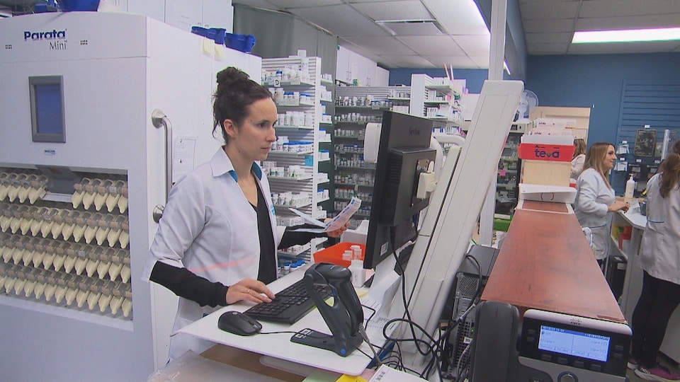 Une pharmacienne devant un écran traite la prescription d'un patient.