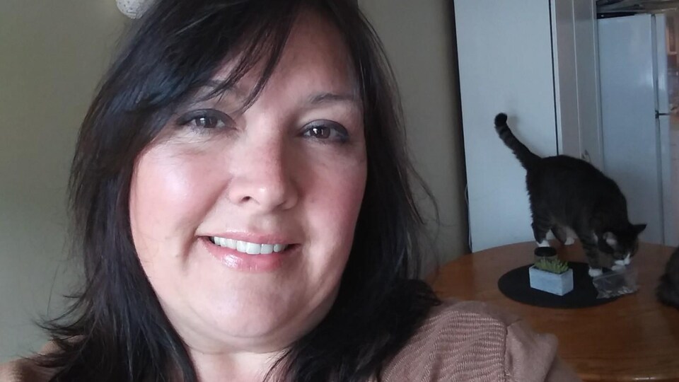 Isabelle Villeneuve avec un chat en arrière plan sur la table de la cuisine