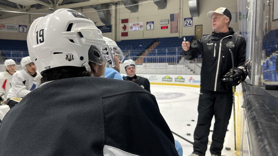 Jim Hulton gives instructions to his players.  Patrick LeBlanc, foreground, listens intently.