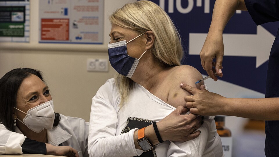Une femme se fait administrer la quatrième dose.