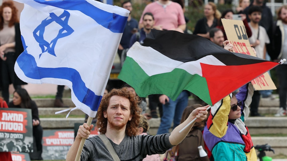 Un jeune homme brandissant les drapeaux palestinien et israélien.
