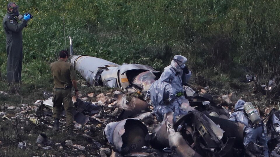 Des membres des forces de sécurité israéliennes examinent les restes de l'appareil de type F-16 qui s'est écrasé.