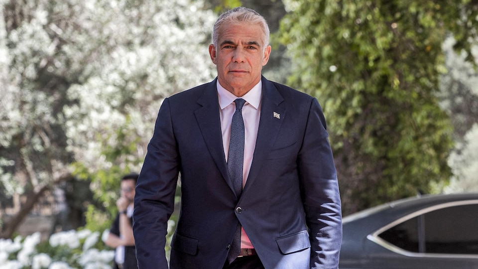 Yaïr Lapid marche après être sorti d'une voiture.