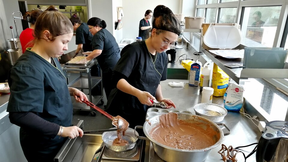 Deux personnes préparent un gâteau au chocolat à l'aide d'outils de cuisine.