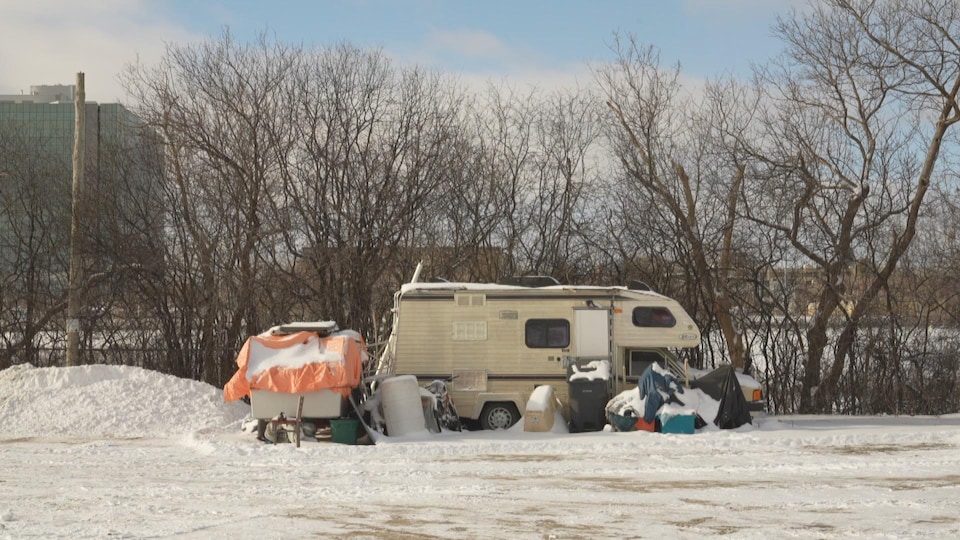 A recreational vehicle surrounded by debris and containers is parked near a small wood near Interstate 50 in Gatineau.