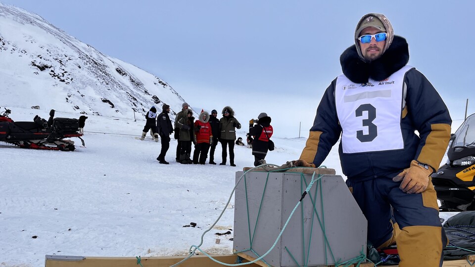 Un homme portant un dossard pose sur son traîneau, Kangiqsujuaq , Nunavik, mars 2023. 