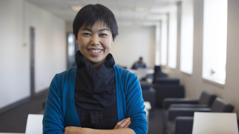 Portrait de Izumi Sakamoto souriante avec les bras croisés.