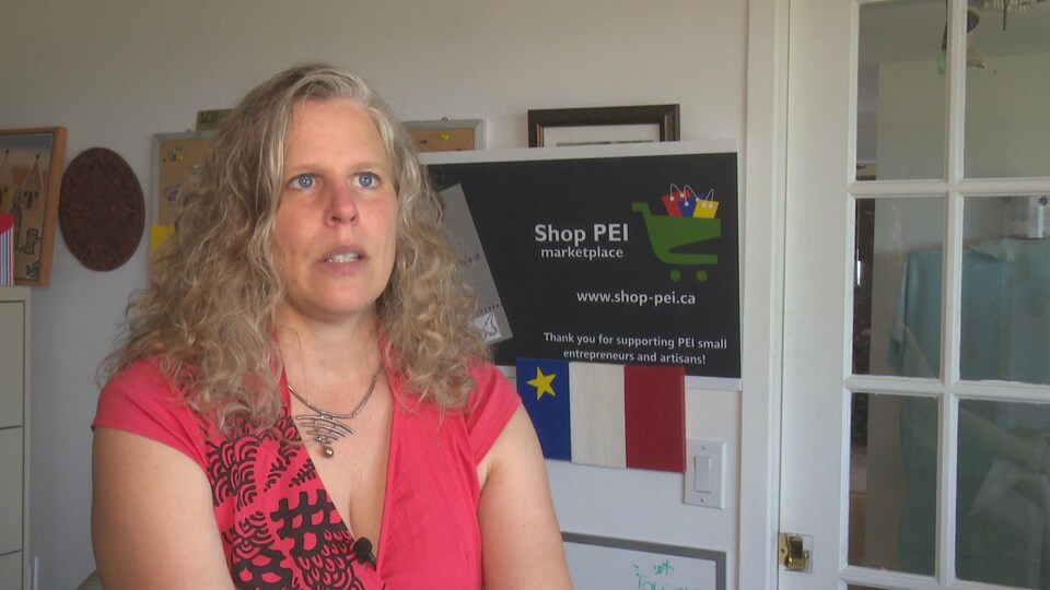 Jacinthe Lemire en entrevue devant une affiche de Shop PEI.