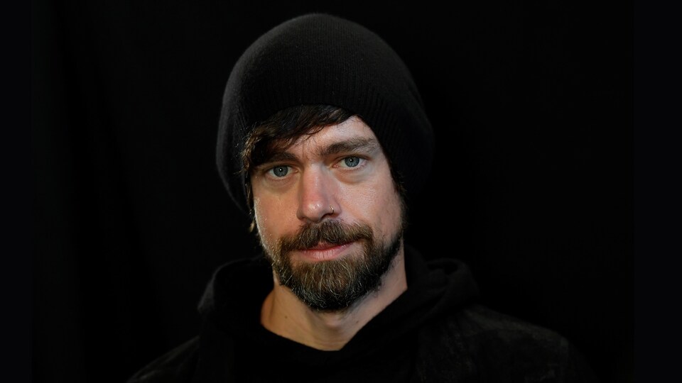 Jack Dorsey, un homme barbu avec une tuque, regarde la caméra dans une photo studio.