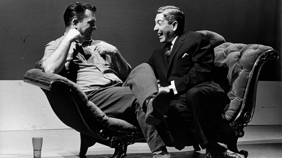 Jack Kerouac et Fernand Séguin qui rient assis sur un divan.