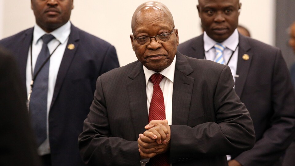 Jacob Zuma marche escorté par deux hommes.