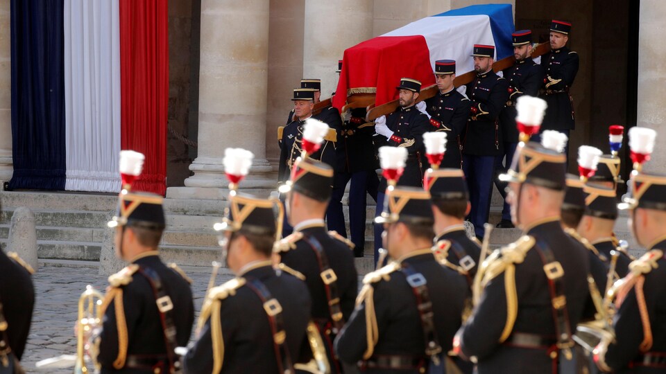 Les gardes descendent des marches avec le cercueil recouvert du drapeau français.