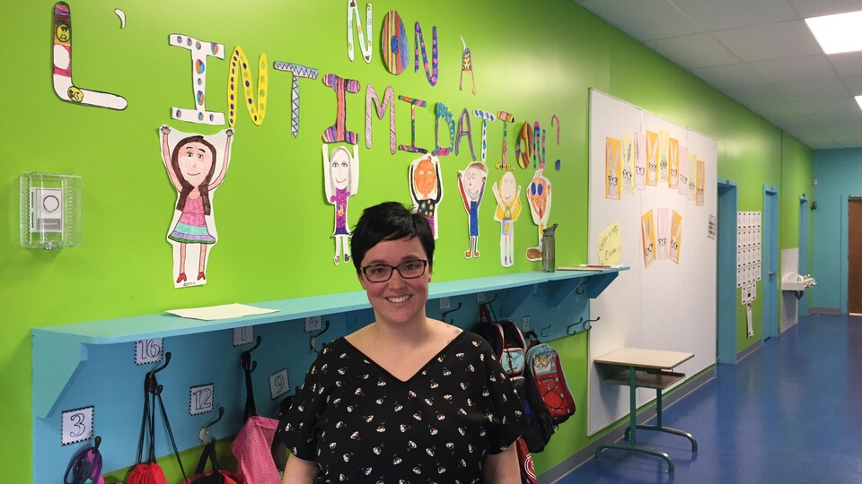 Une enseignante pose dans le couloir d'une école primaire.