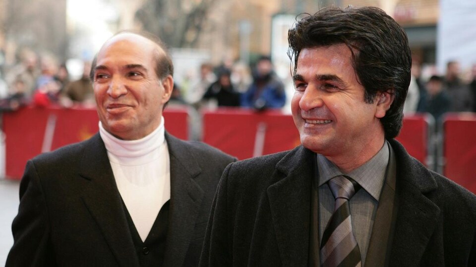 Deux hommes sourient pour les objectifs sur un tapis rouge. 