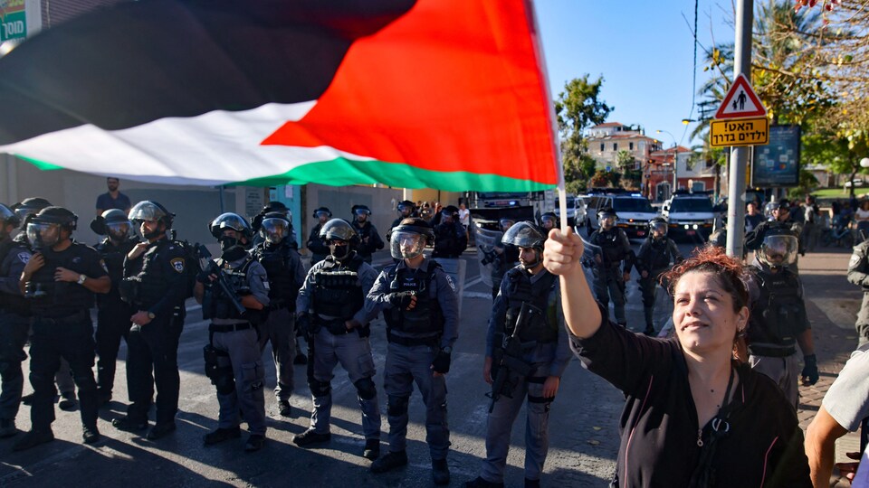 Une femme brandit un drapeau dans la rue.