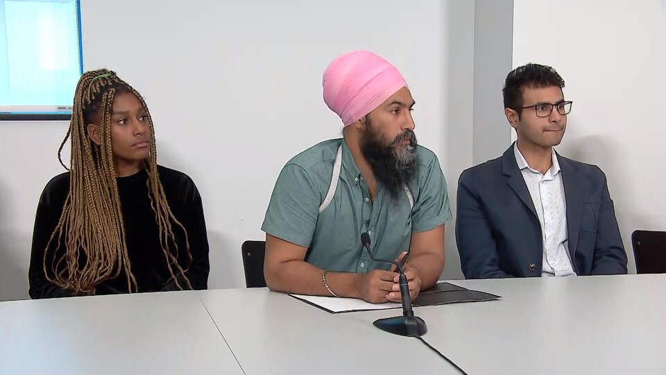 Jagmeet Singh est assis à une table, entouré d'une jeune femme et d'un jeune homme.
