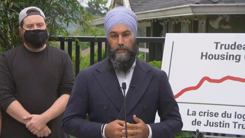 Jagmeet Singh se tient devant un micro, les mains jointes.