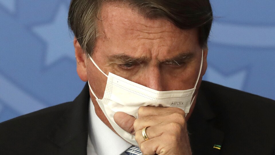 Gros plan de Jair Bolsonaro qui tousse dans son masque.