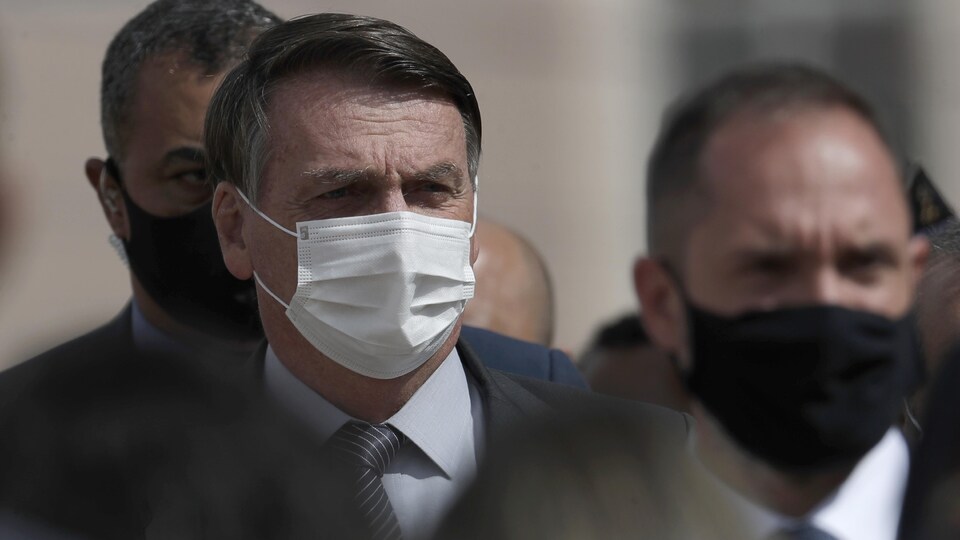 Jair Bolsonaro, masqué, entouré d'autres hommes.