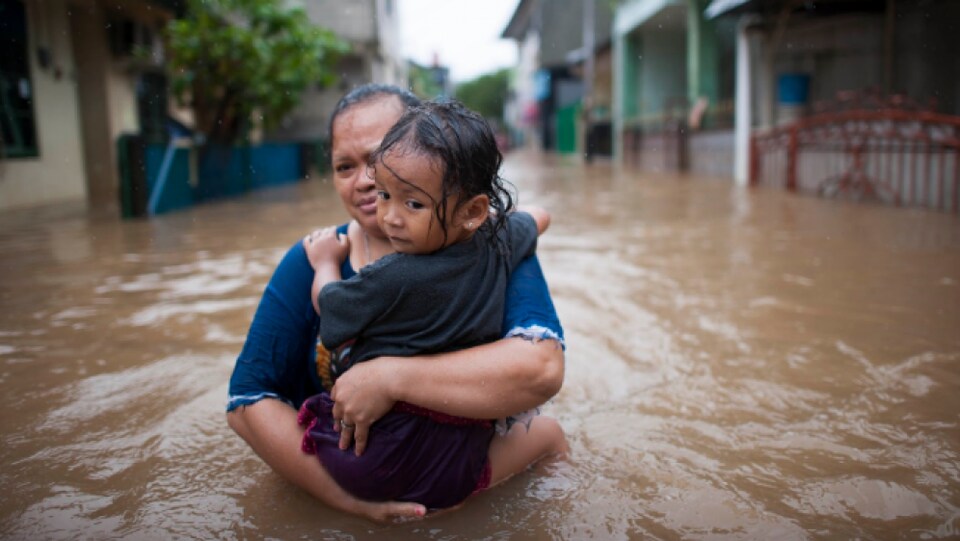 Une mère et sa fille marche dans une rue inondée.