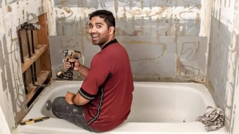 Un homme effectue des travaux de rénovation dans une salle de bains.