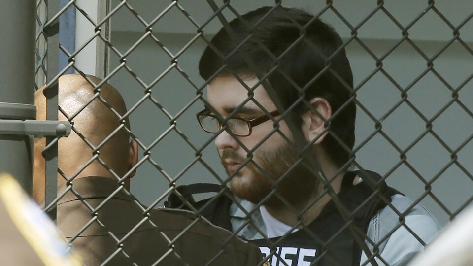 James Alex Fields marche derrière une grille.