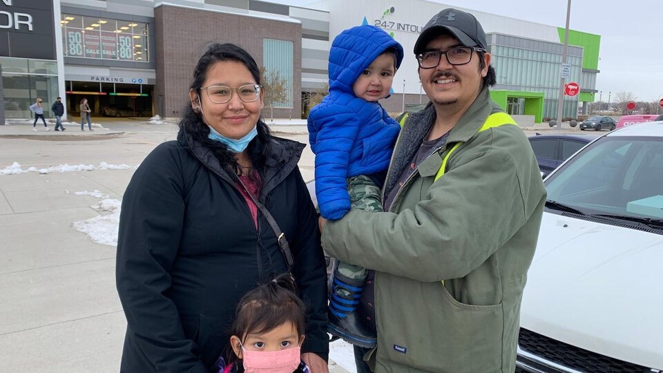 Des parents et leurs deux enfants devant un centre d'appel.