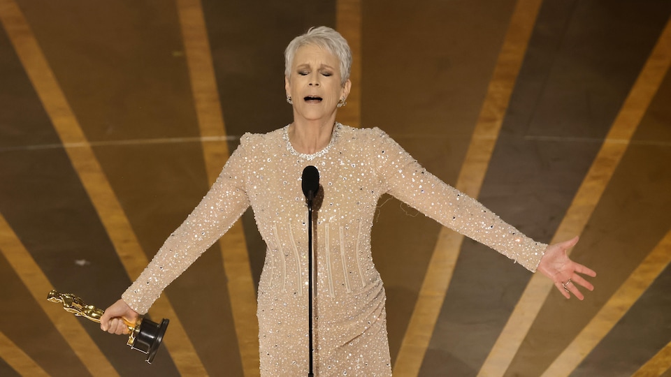 L'actrice ouvre les bras en tenant son Oscar sur scène. 