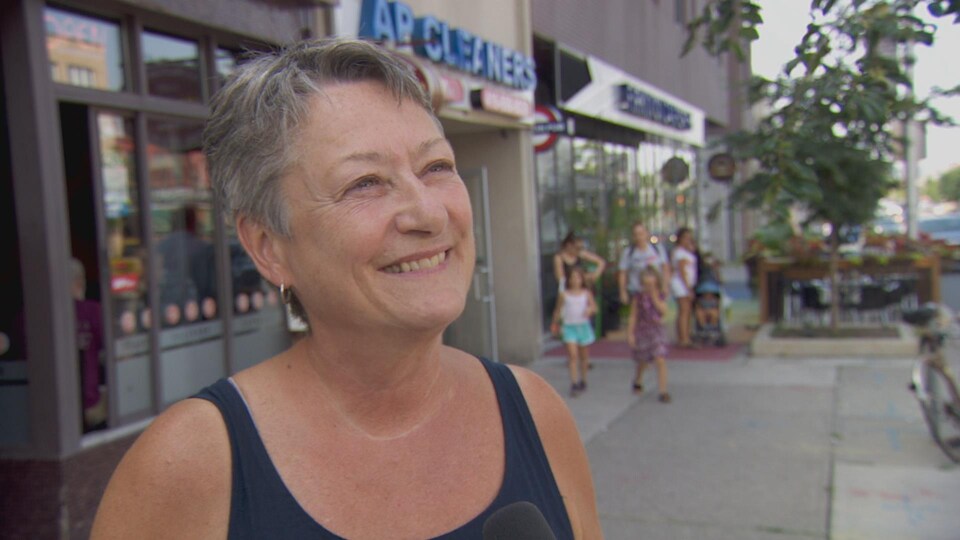 Une femme sourit dans la rue au micro de Radio-Canada.