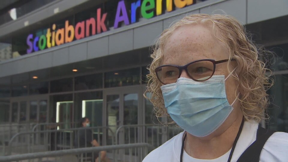 A masked woman speaks to the camera outside the Scotiabank arena.
